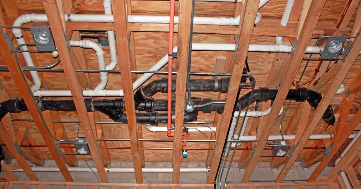 Overhead plumbing and mechanical rough-in with drain, water and vent piping running through ceiling joists